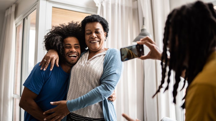 A man takes a photo of a family at home.
