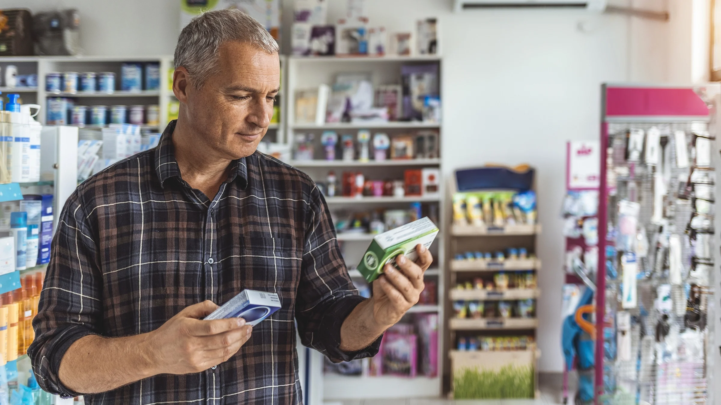 A man compares two medical products in a pharmacy.