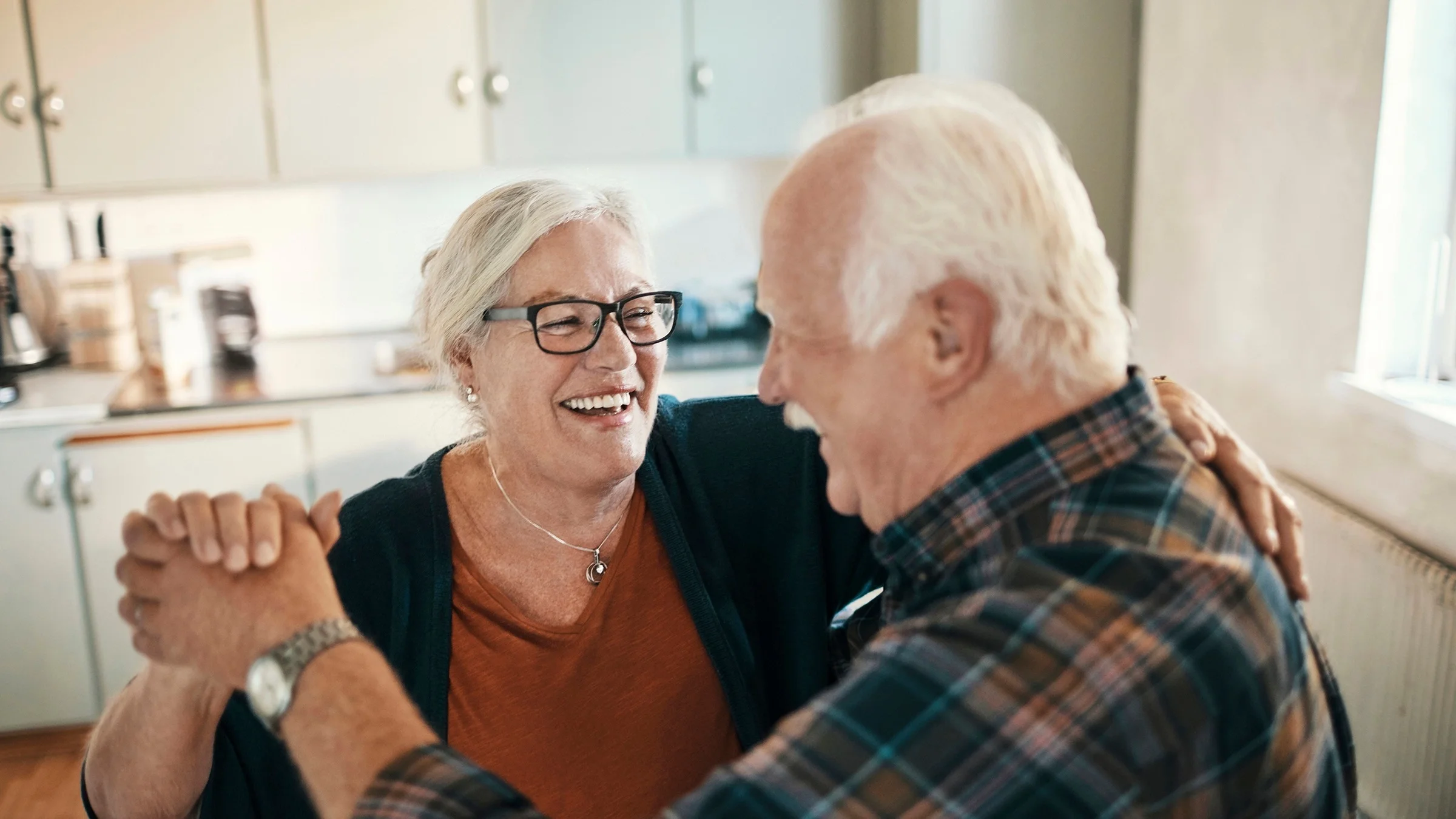Senior couple dancing in their kitchen.