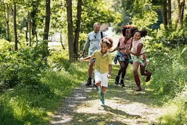 A family running through the trees on a hiking trail–including one man, one woman and two children.
SolStock/E+ via Getty Images