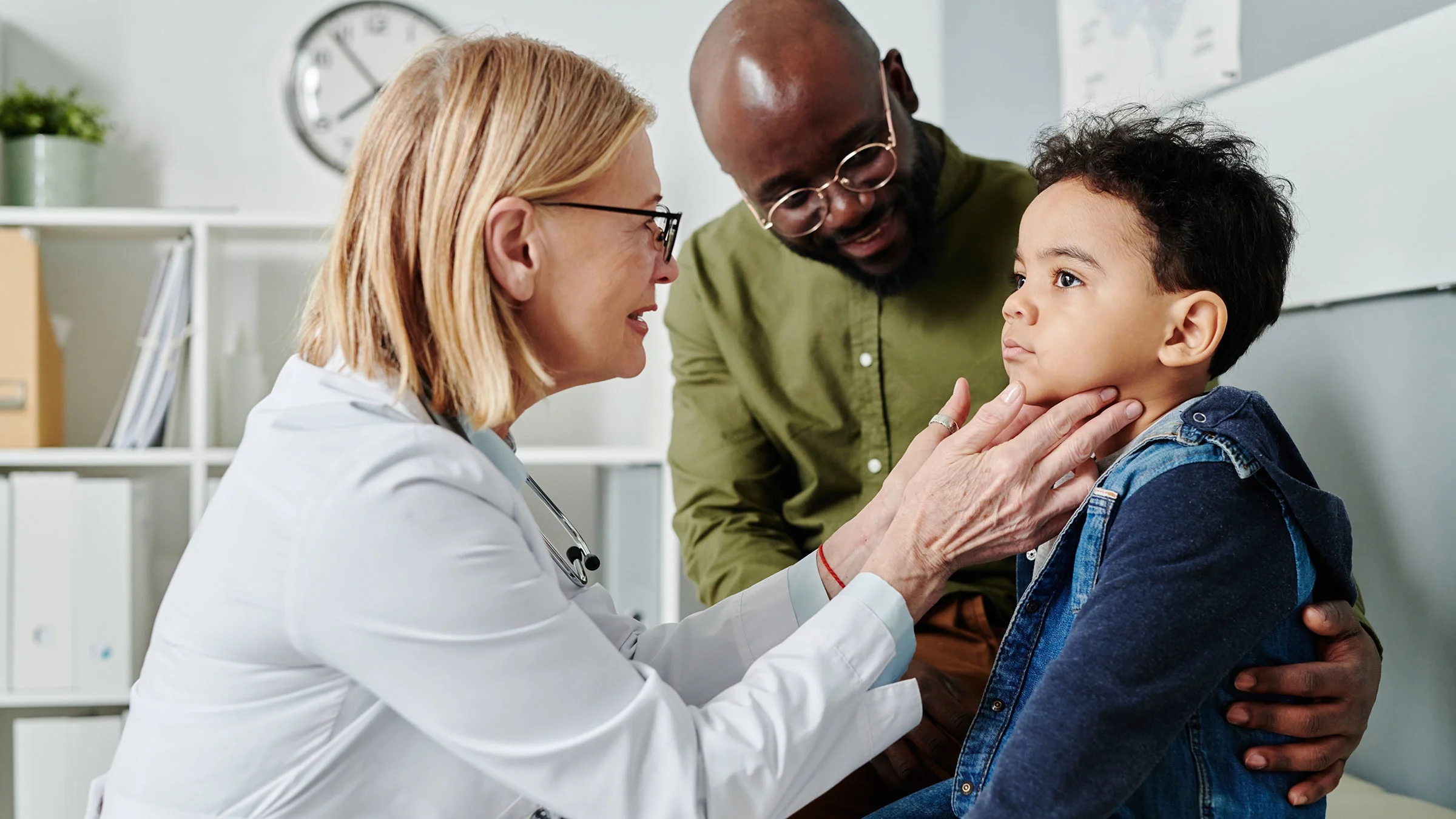 A healthcare provider is checking a child's thyroid.