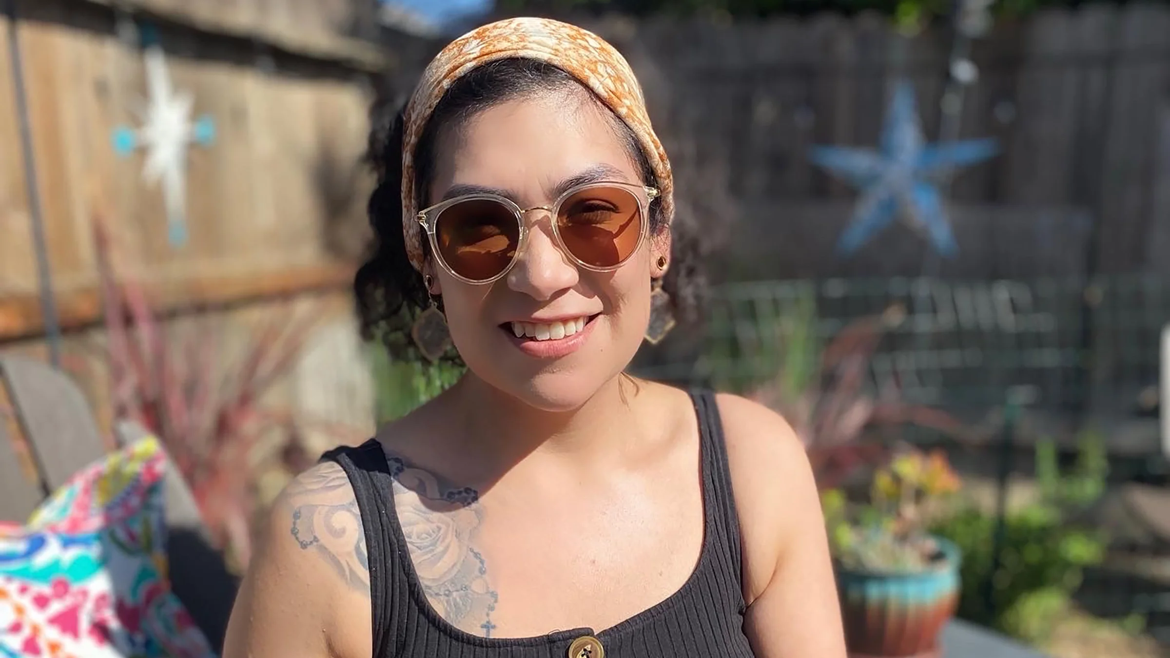 Portrait of migraine patient Erika Cortez wearing sunglasses outdoors in a backyard.