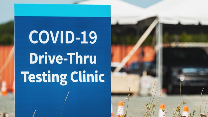 Blue signage in parking lot for a drive-thru COVID-19 testing site