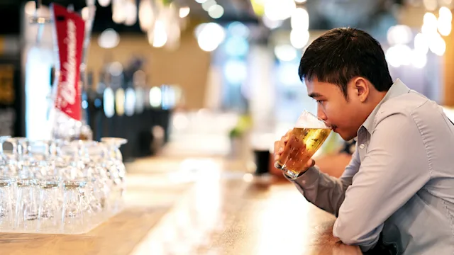 muscle-relaxants: man drinking beer alone at the bar 1126372219