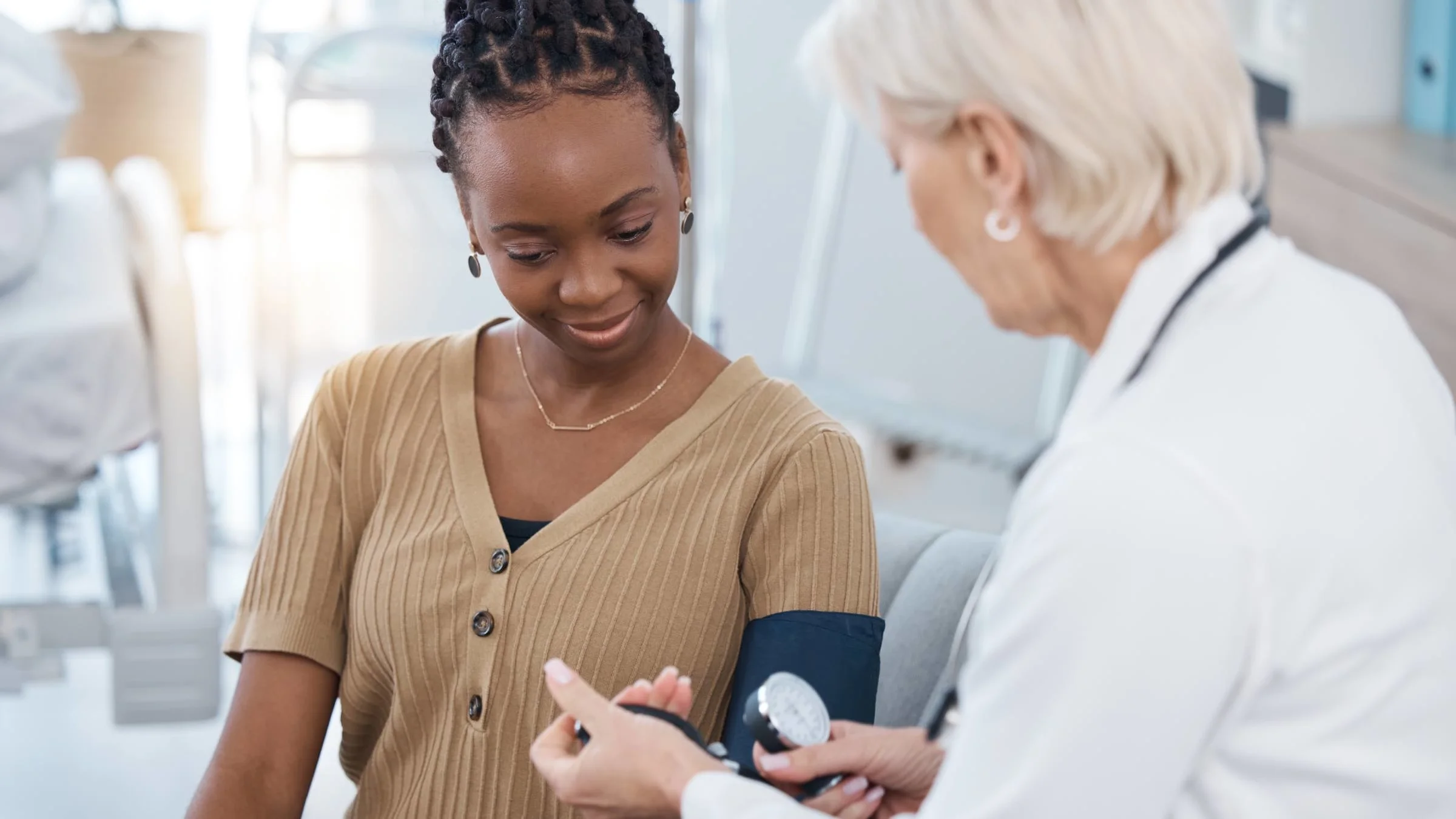 An African American adult getting their blood pressure checked by a doctor.