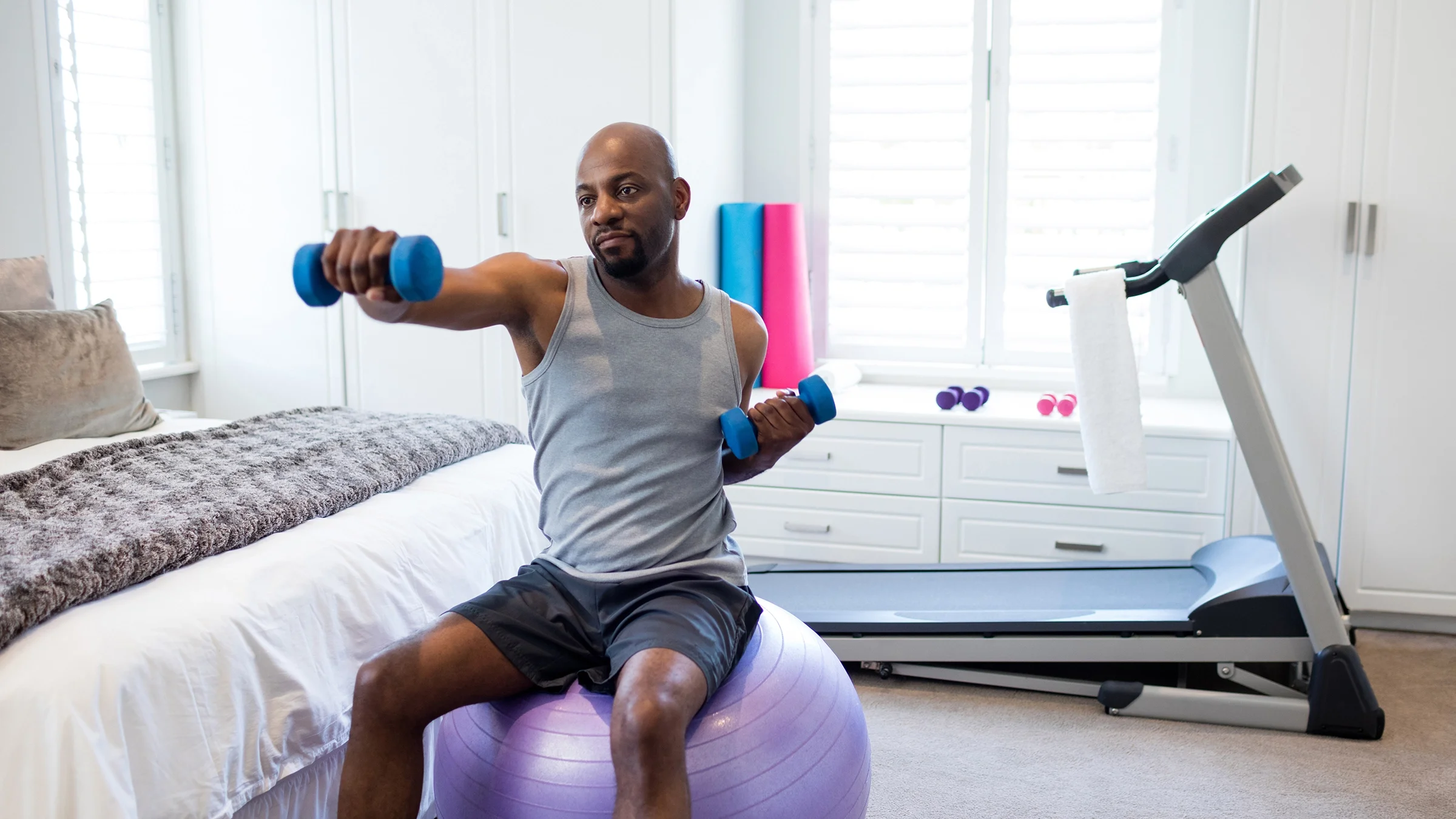 A man works out at home using equipment in his room.