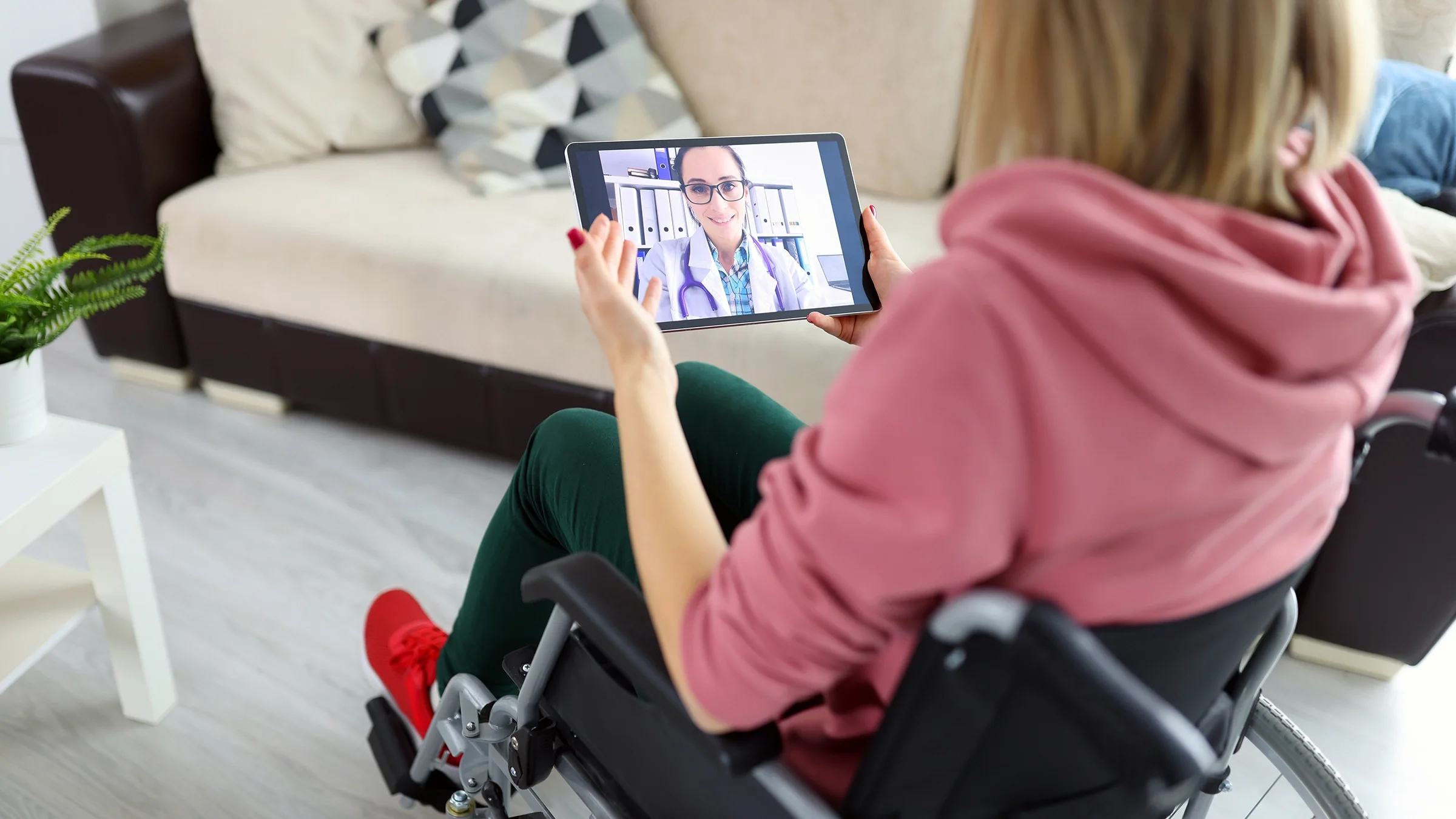 A woman in a wheelchair speaks with her doctor during a telehealth call.
