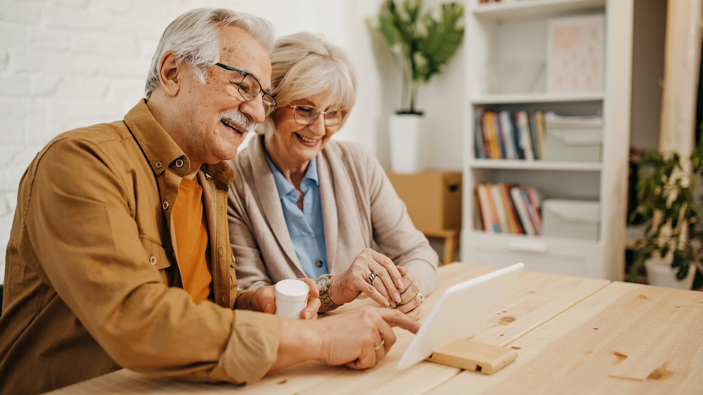 A senior couple talking about pill bottle in a telehealth call.