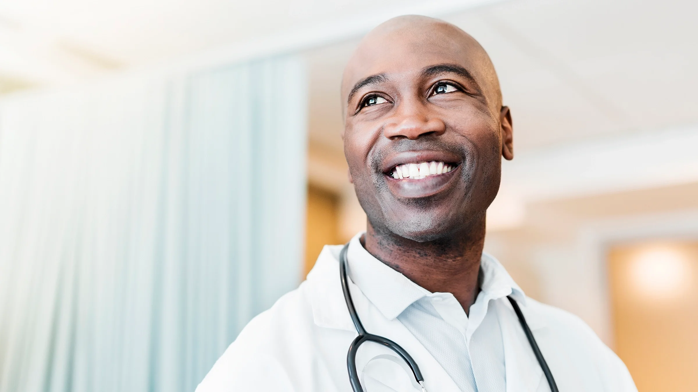 Close-up portrait of a doctor smiling and looking up hopefully.