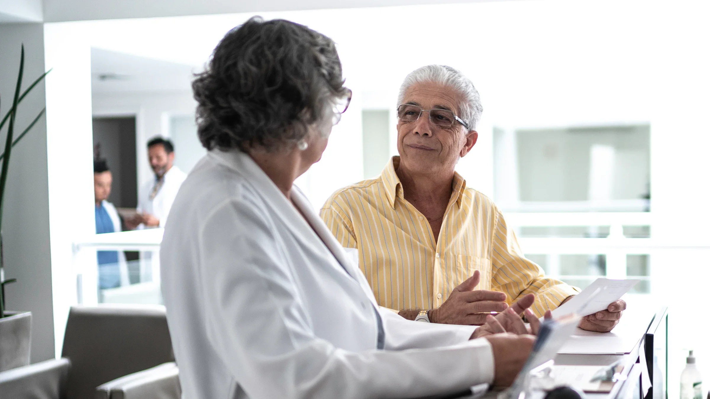 An older adult is consulting with his doctor at the front desk.
FG Trade/E+ via Getty Images