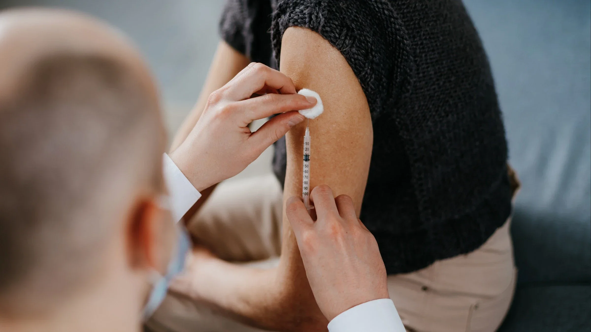 Close-up cropped shot of a doctor giving a female patient a vaccine shot.
YurolaitsAlbert/iStock via Getty Images