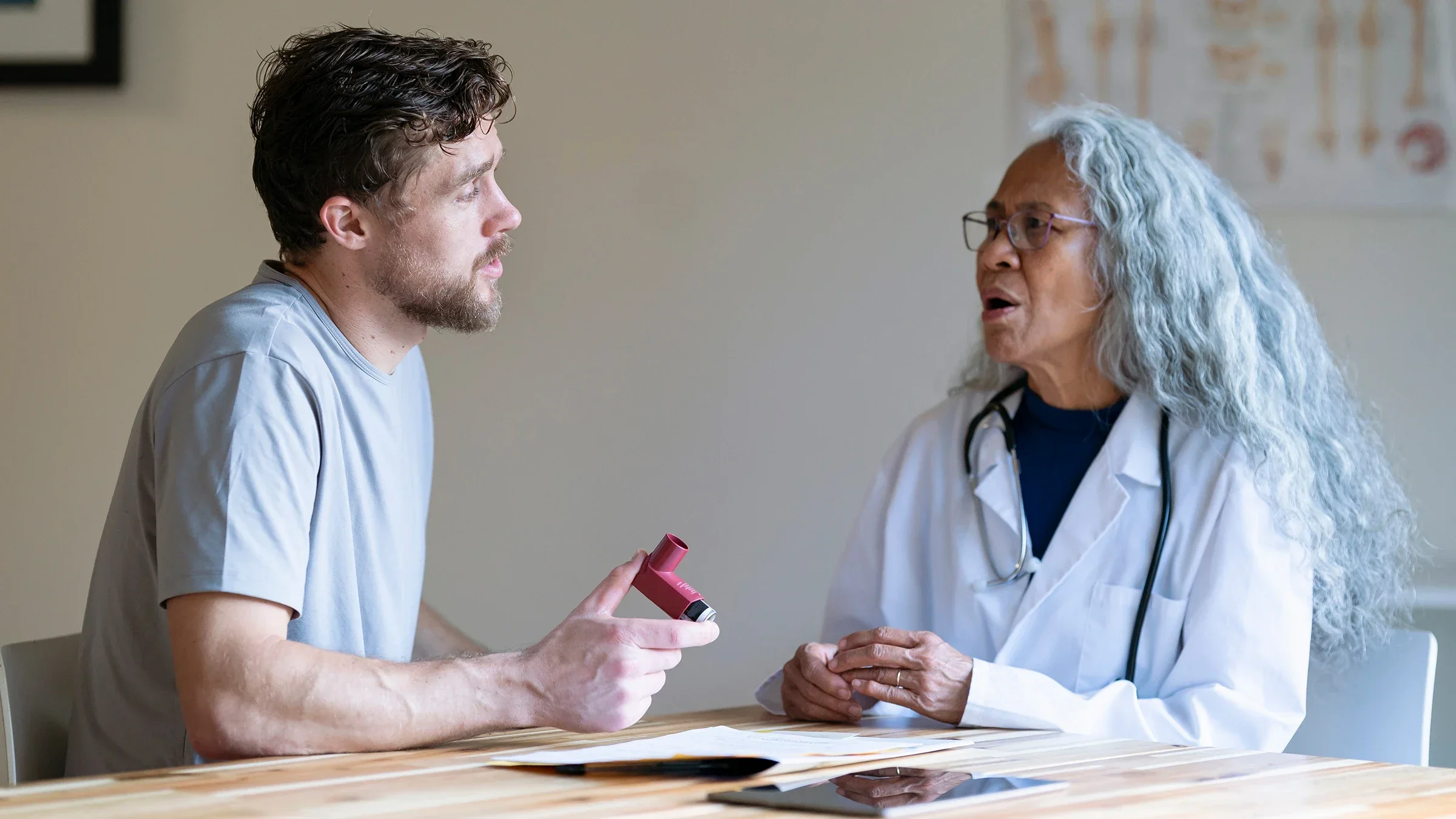 A patient discusses how to use an asthma inhaler during a medical consultation.
Fly View Productions/E+ via Getty Images