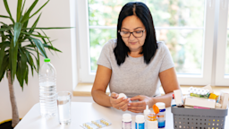A woman reads the label on a pill bottle while sitting at a dining table.
Constantinis/E+ via Getty Images Plus