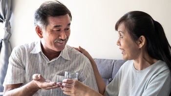 Health: fenofibrate: woman helping husband take pills-1315200661
