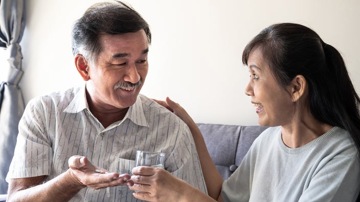 Senior man taking medication with his wife's help and encouragment.