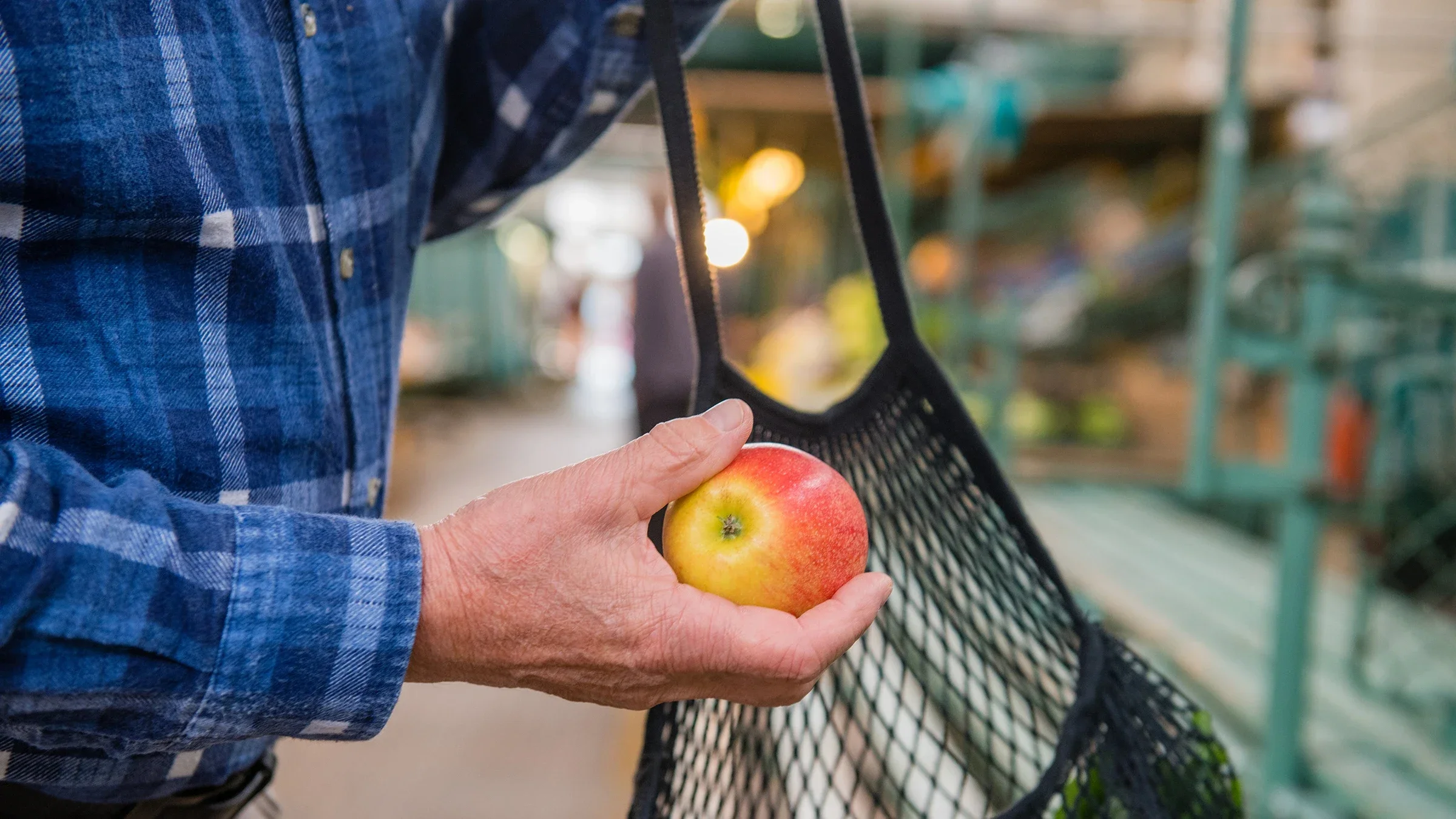 Close-up hand placing an apple in a reusable bag
AlenaPaulus/iStock via Getty Images Plus