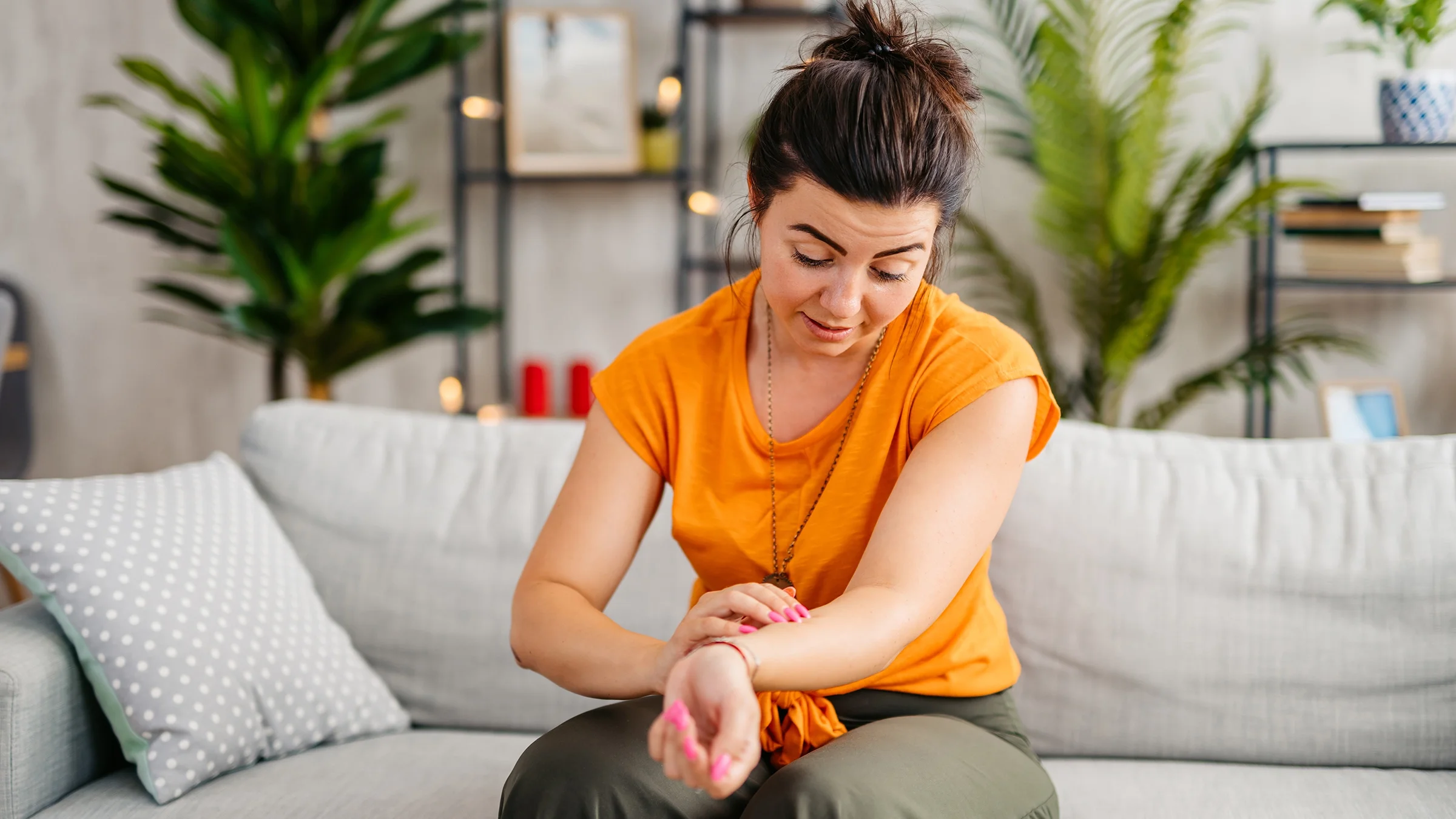 A woman is scratching her forearm.