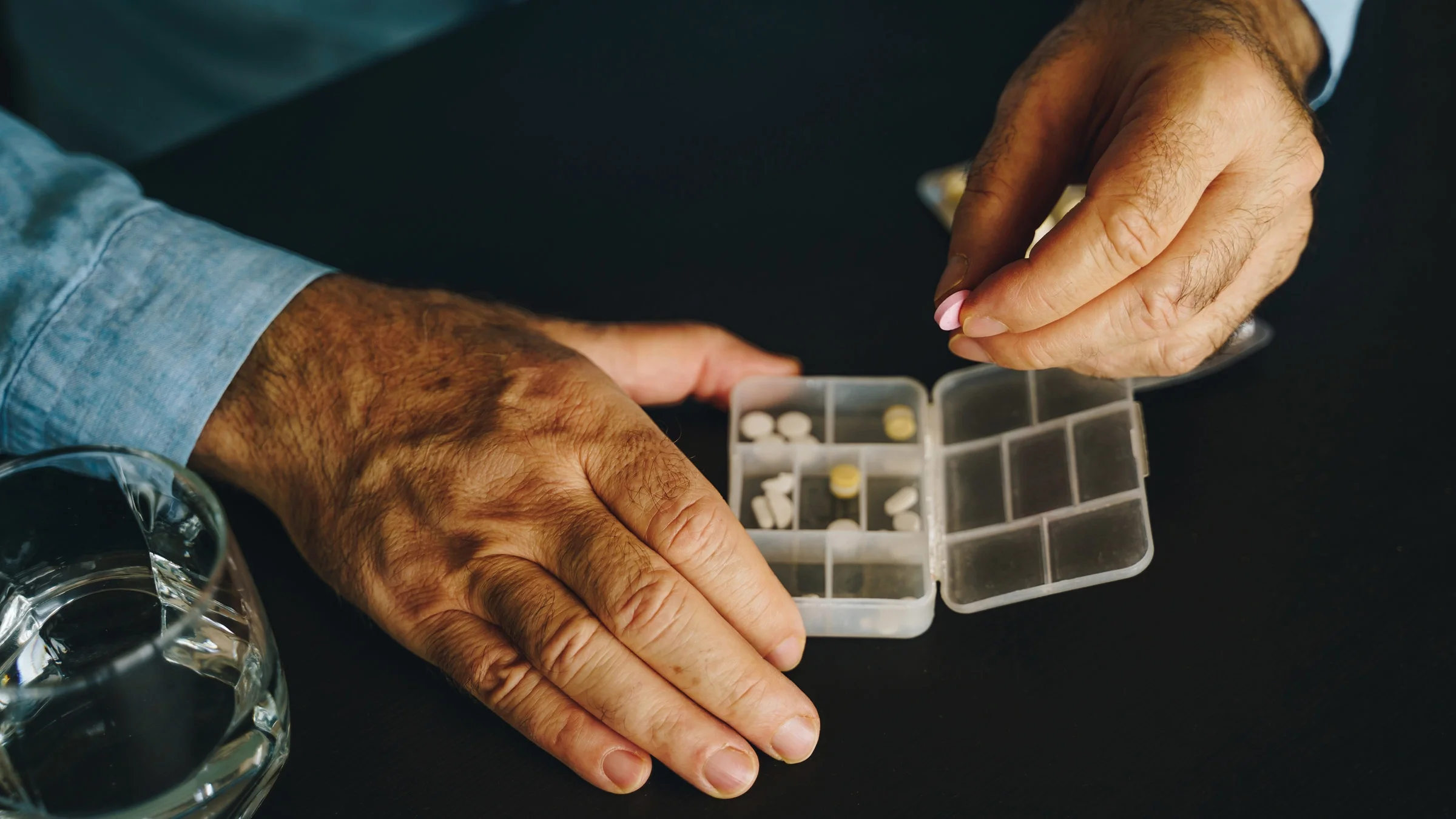 Hombre mayor organizando sus pastillas en un organizador de pastillas.