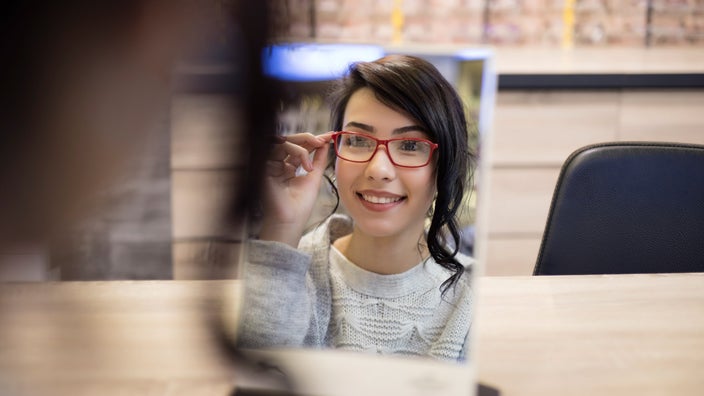 A person trying on glasses in the mirror at a store.