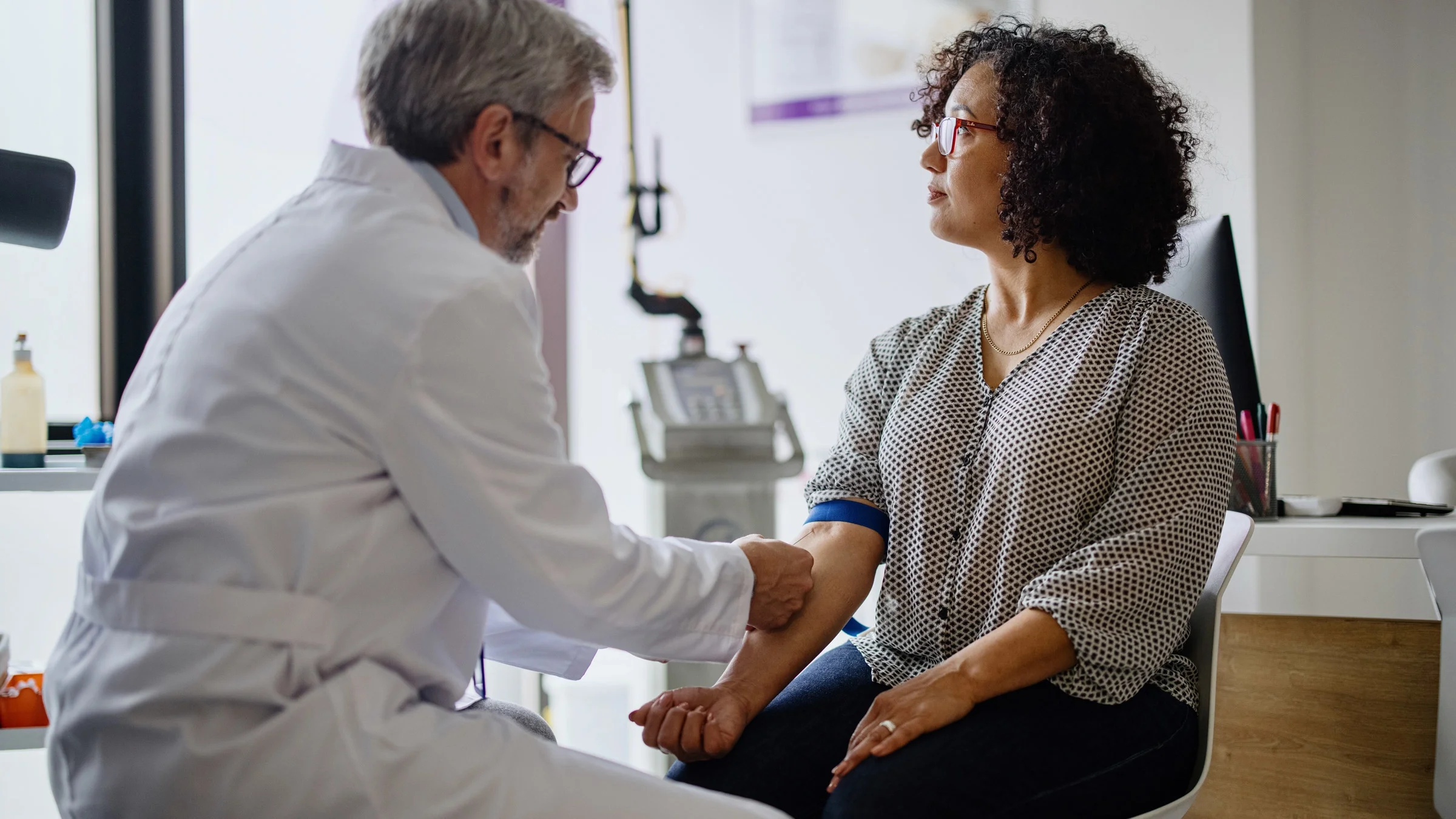 A phlebotomist is preparing a woman for a blood draw.