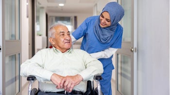 Caregiving: nurse pushing man in wheelchair 1404962439