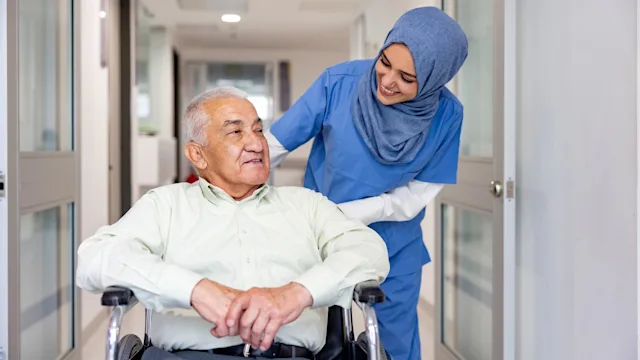Caregiving: nurse pushing man in wheelchair 1404962439