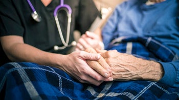 Health: Parkinson's disease: closeup nurse holding elderly patients hands-895087964