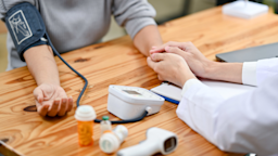A doctor holding a patient's hand, while taking blood pressure. 
BongkarnThanyakij/iStock via Getty Images Plus 