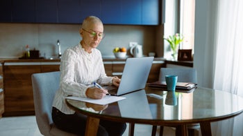 Cancer: UninsuredL cancer patient doing paperwork on laptop 1396903657