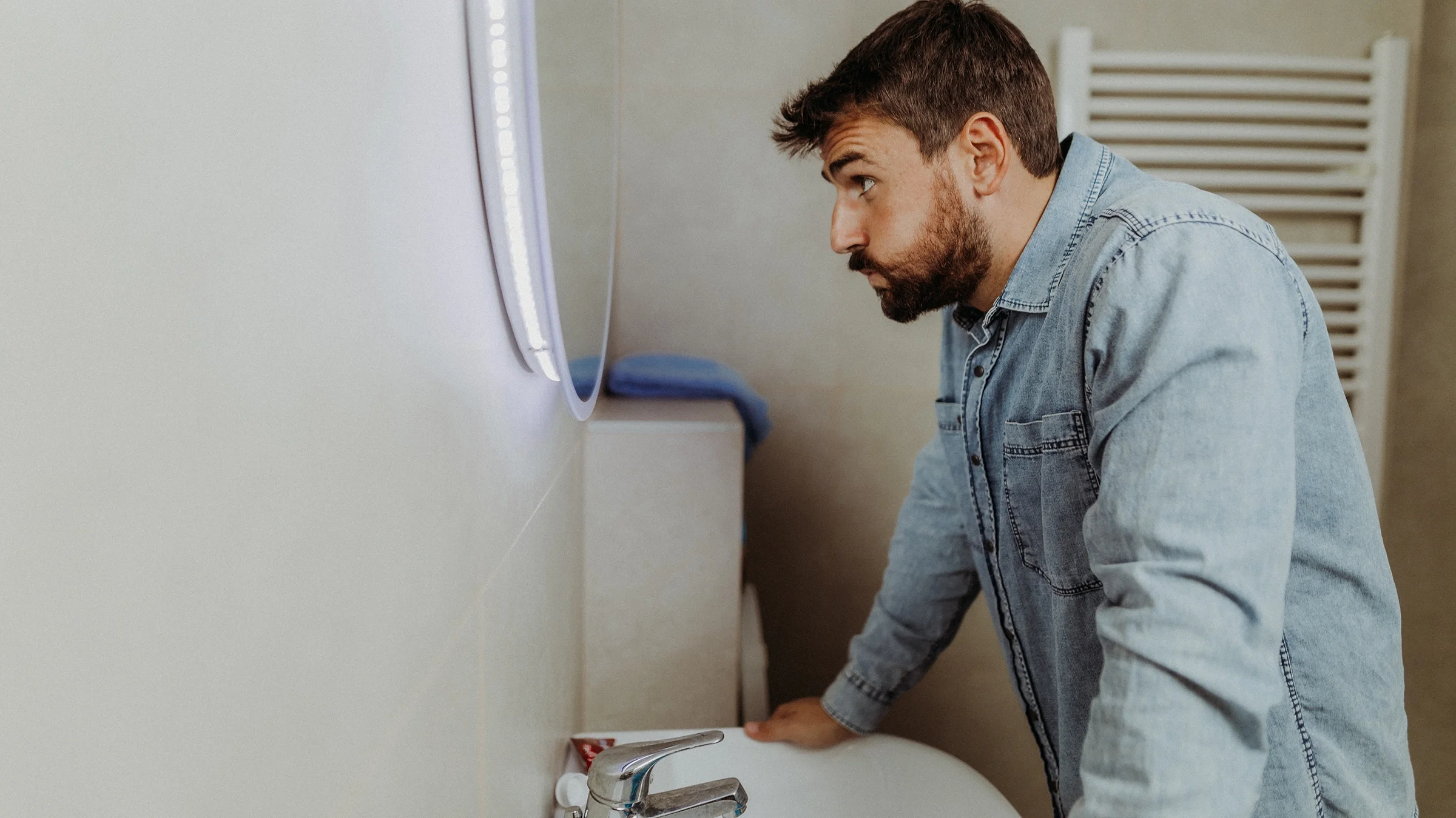 A stressed-out man looks at himself in the mirror.