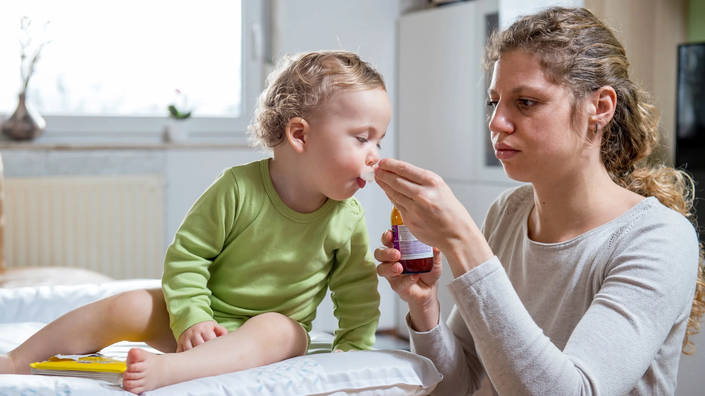A mother giving cold medicine to her baby. 