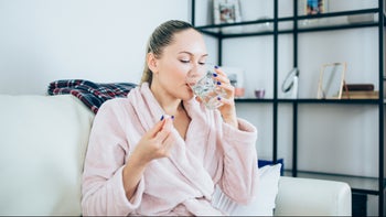 Health: Quinolone antibiotics: woman in robe taking medicine 961034926