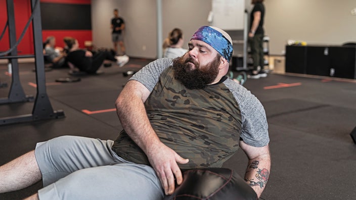 Bearded man working out with a weight ball at the gym.