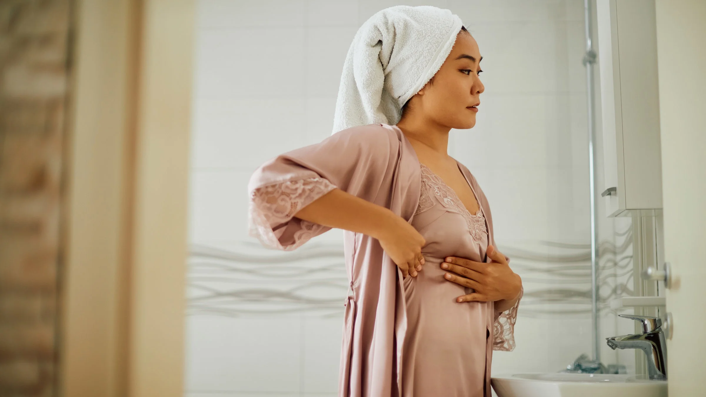 A person conducting in a breast exam in their bathroom mirror.