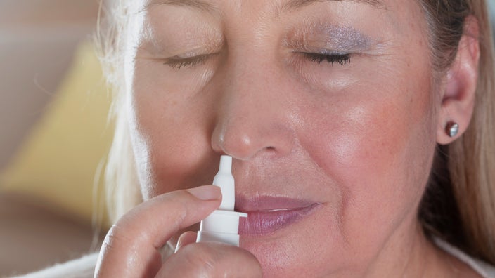 Close-up of someone using a nasal spray.