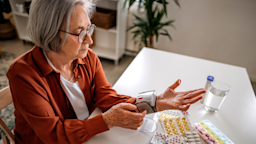 Senior woman taking her vitals with a blood pressure cuff at her kitchen table with pills surrounding her.
eclipse_images/E+ via Getty Images