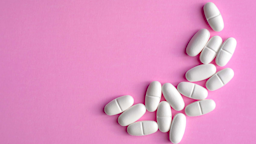 A pile of white oblong pills on a bright-pink background.
Maria Rzeszotarska/iStock via Getty Images
