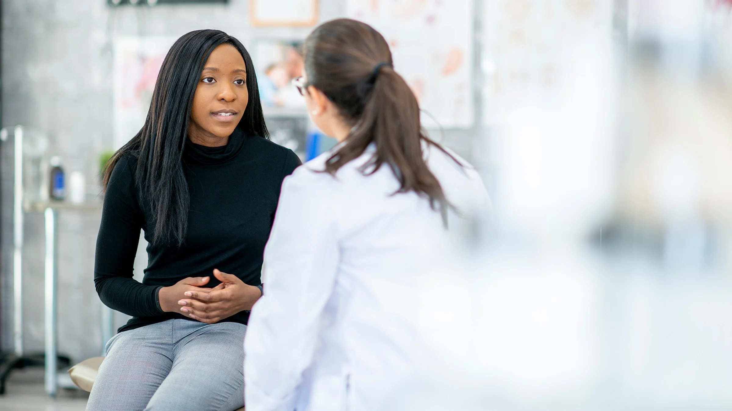 Young Black woman talking with her doctor in the exam room.