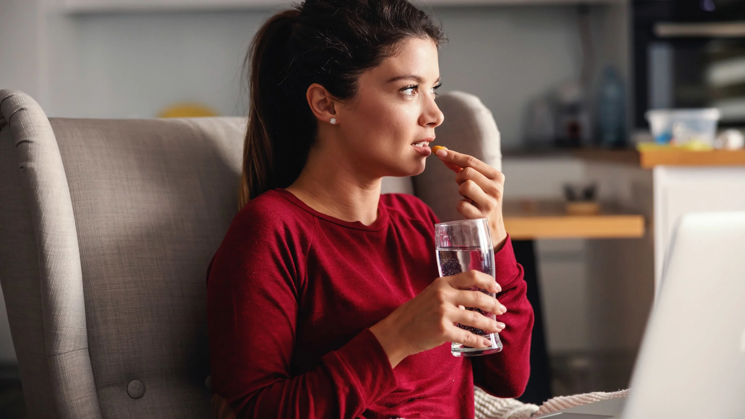 A person taking pill on a couch.