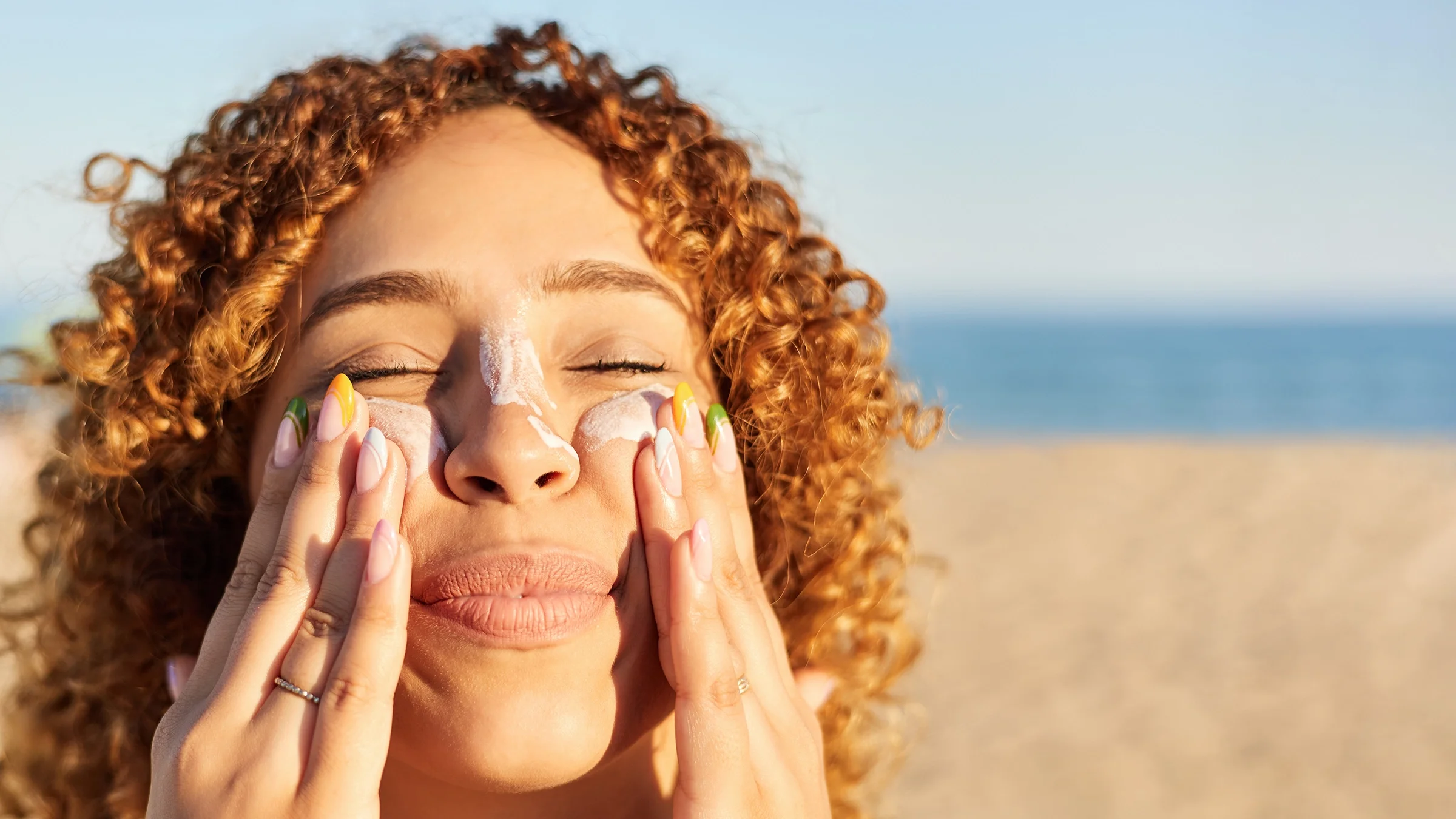 Woman applying sunscreen to her face.