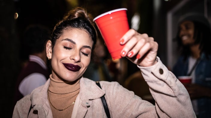 A young drunk partygoer holding a solo cup.