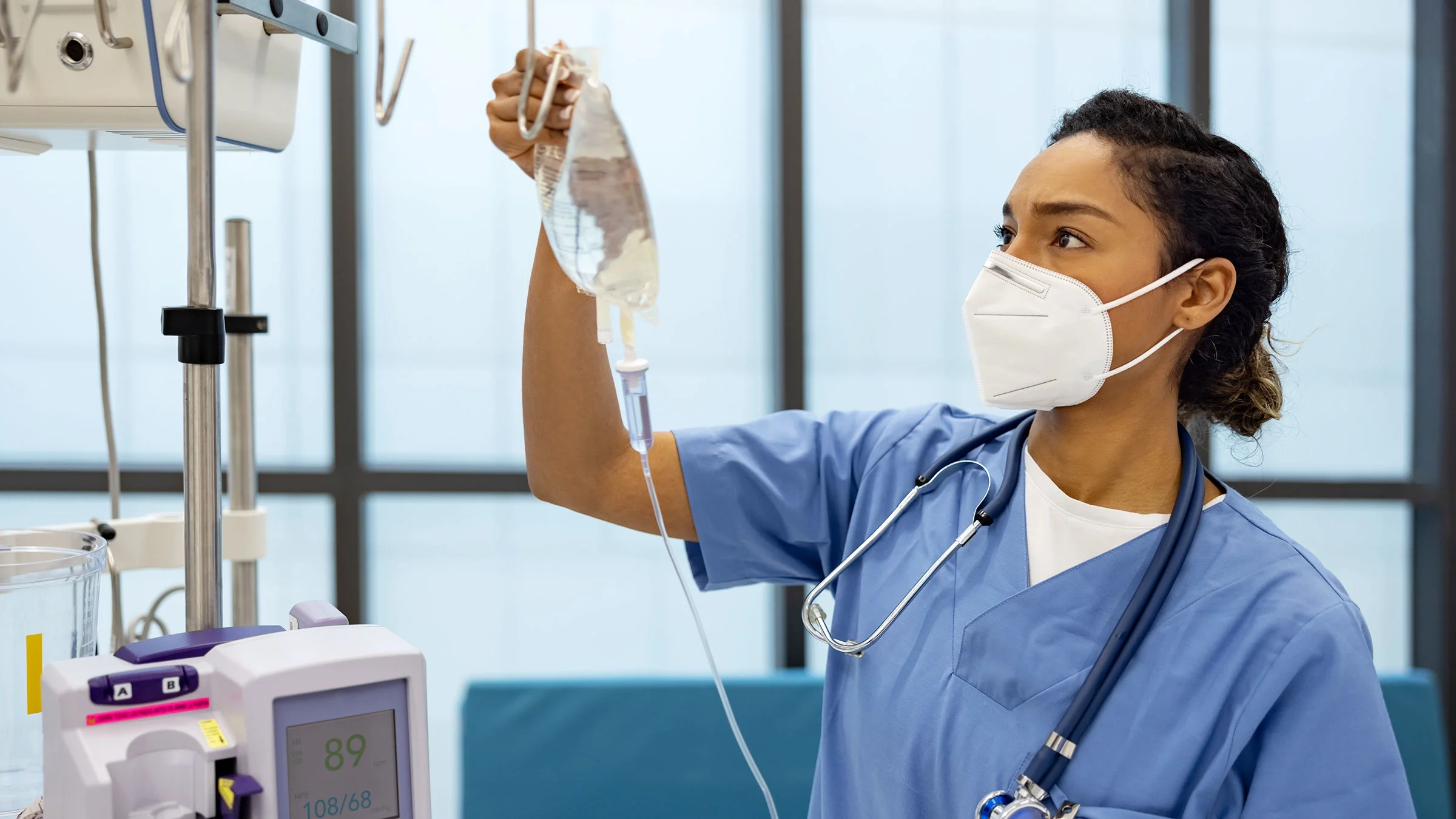 A healthcare professional sets up an IV drip for a patient.