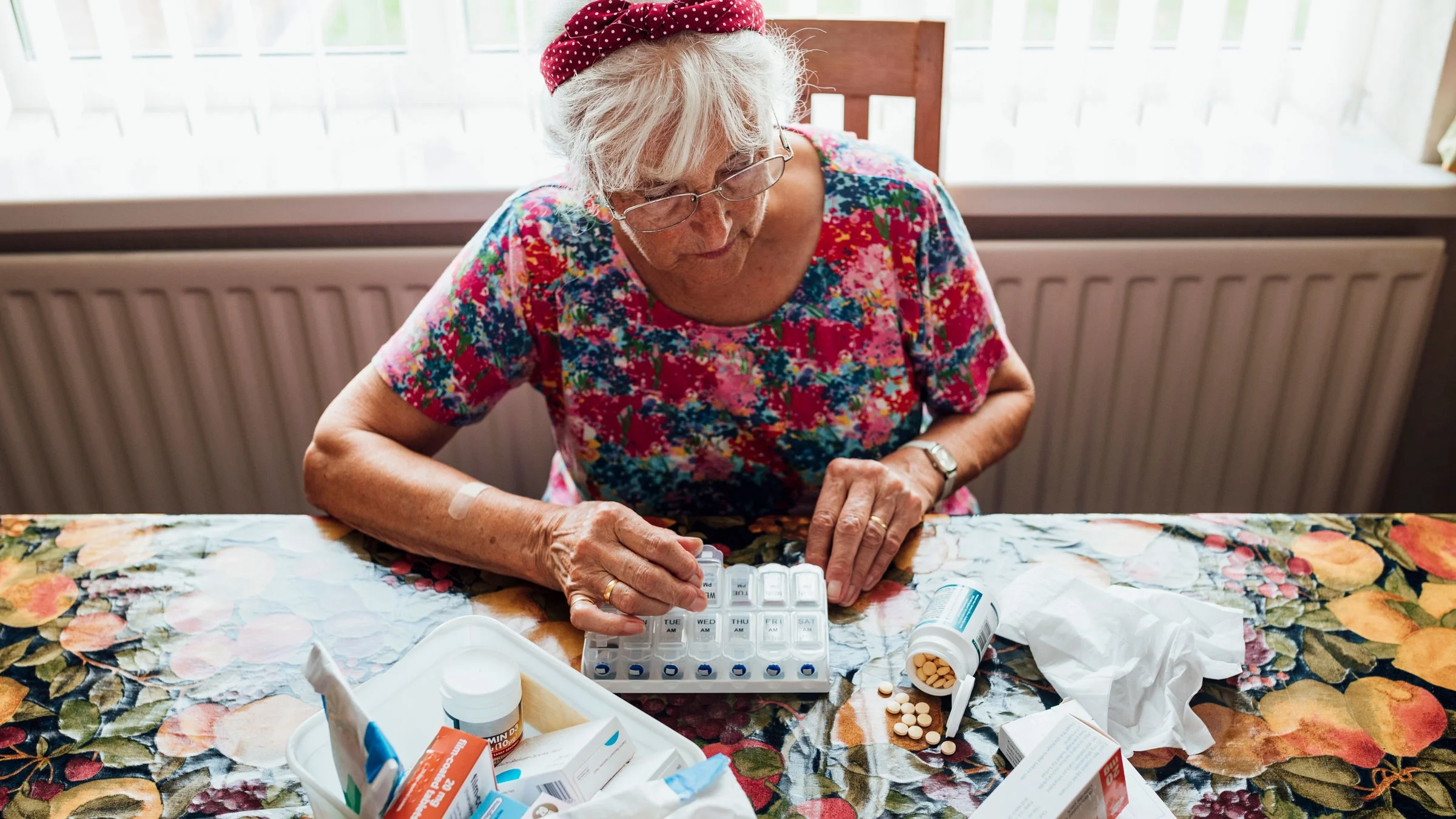 Senior woman sorts through pillbox.