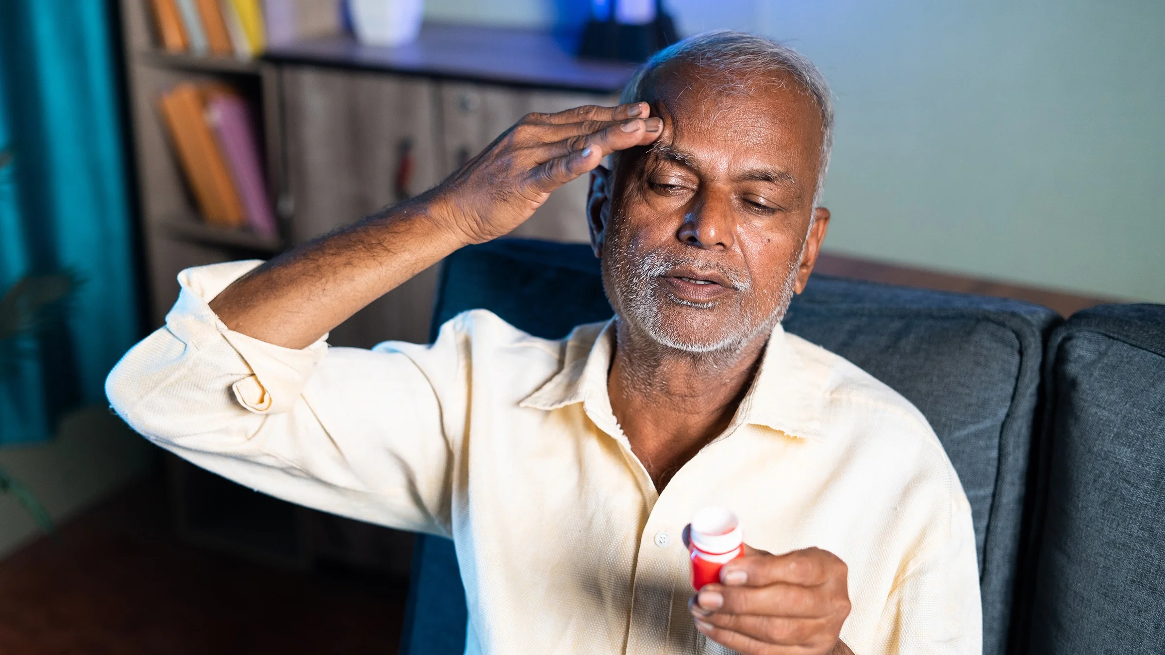 An older man is using pain relief balm for a headache.