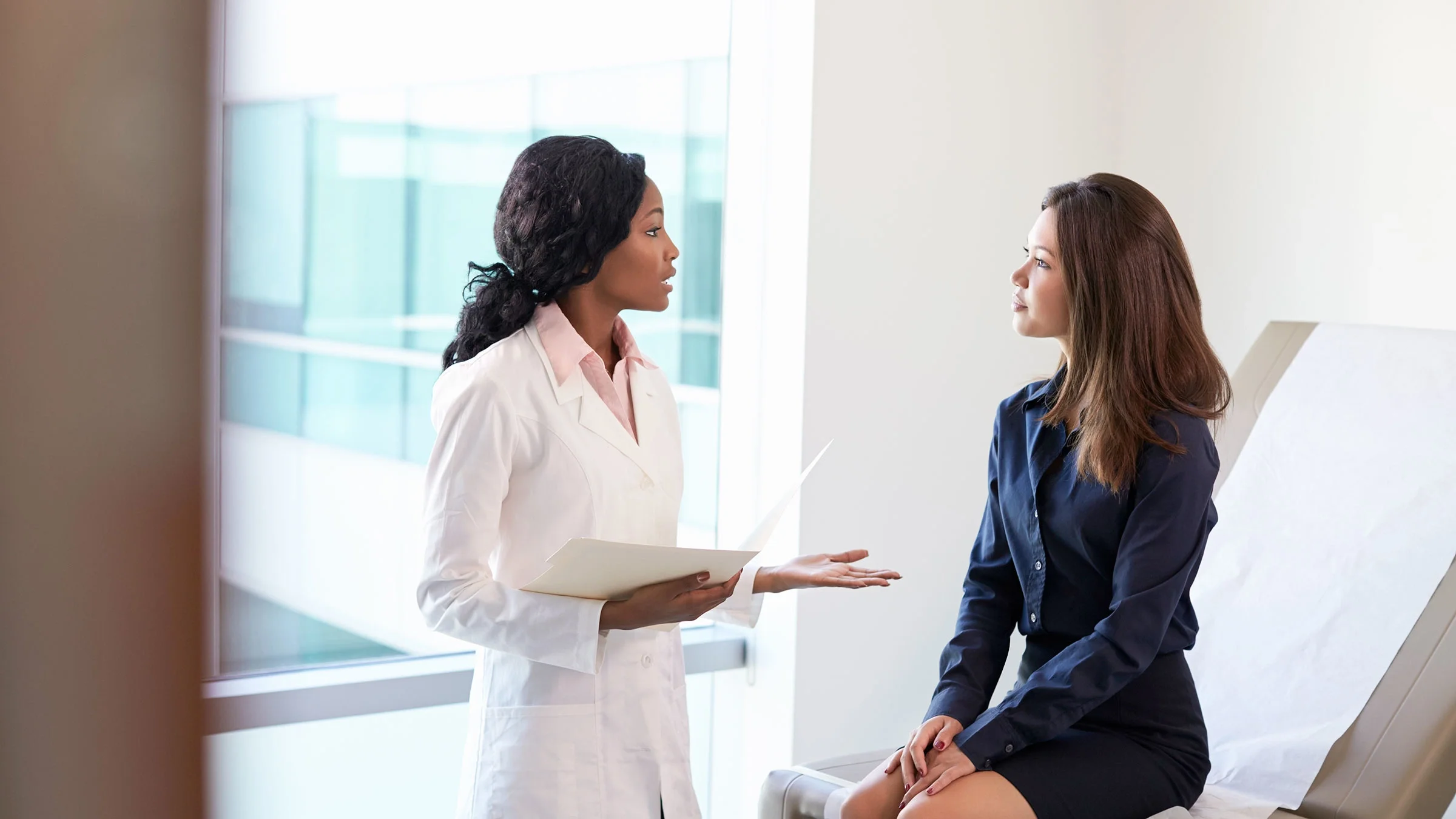 A healthcare provider is meeting with a patient in an exam room.
