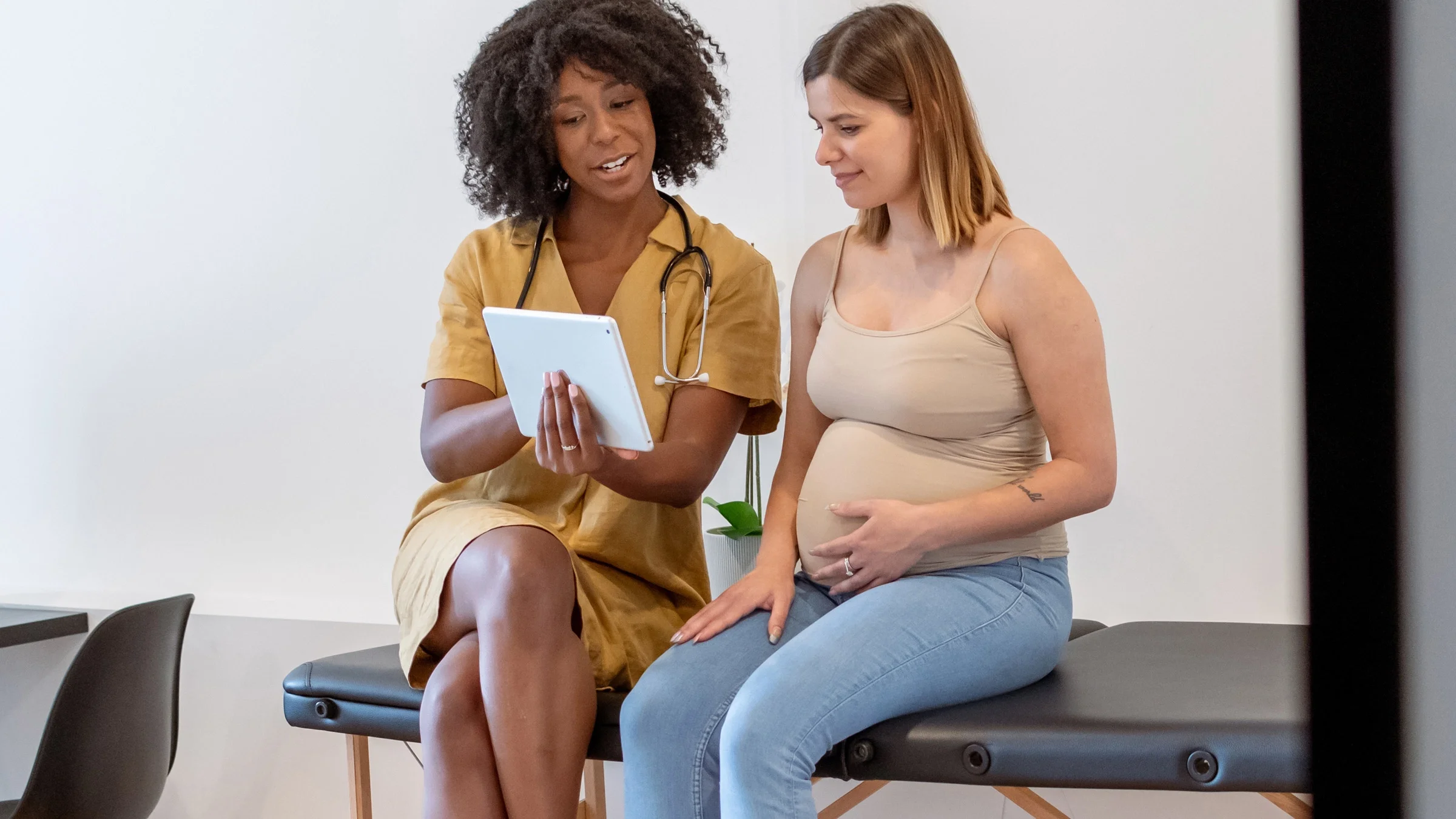 A HCP showing a tablet to a pregnant patient.