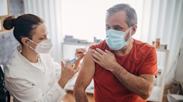 A healthcare provider gives a man a vaccine injection on his right arm.
South_agency/E+ via Getty Images