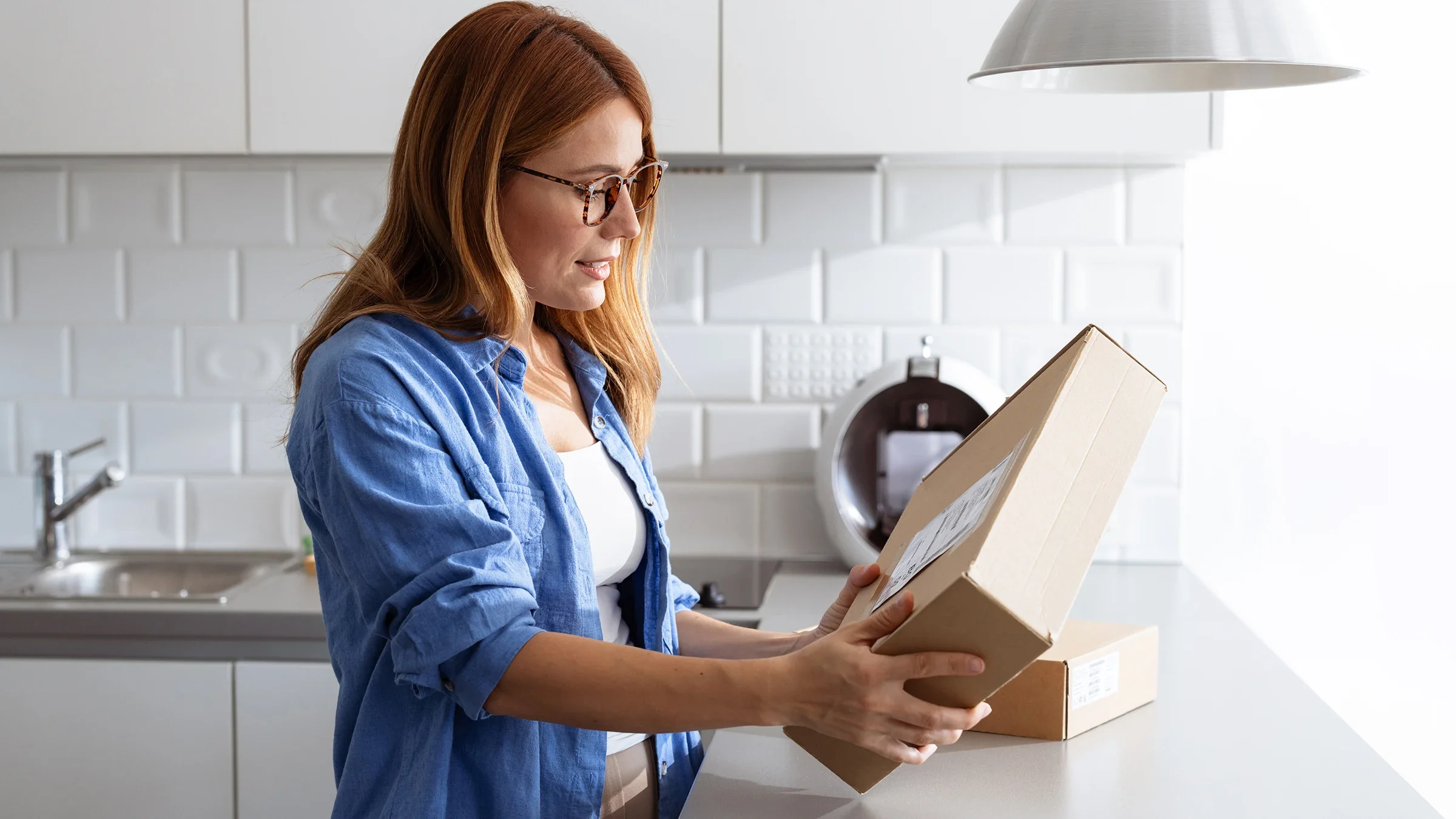 A woman opens a package in the kitchen.
Riska/iStock via Getty Images Plus