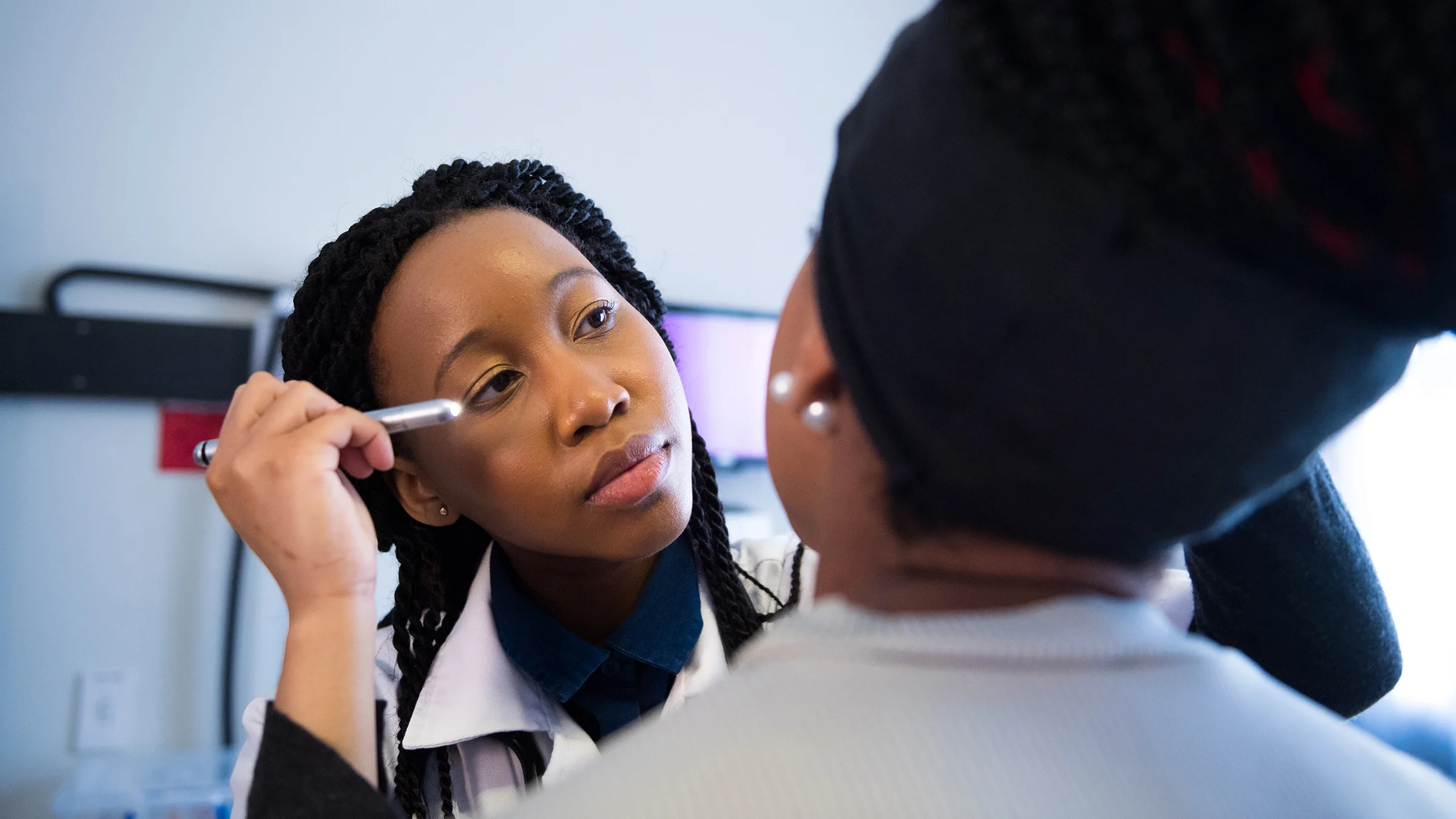 Eye doctor examining woman’s eye with flashlight.