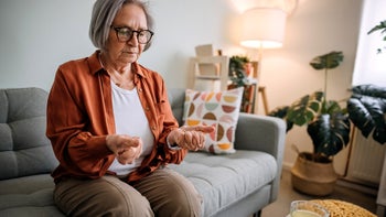 senior woman making fists to check arthritis flair up-1310657868
